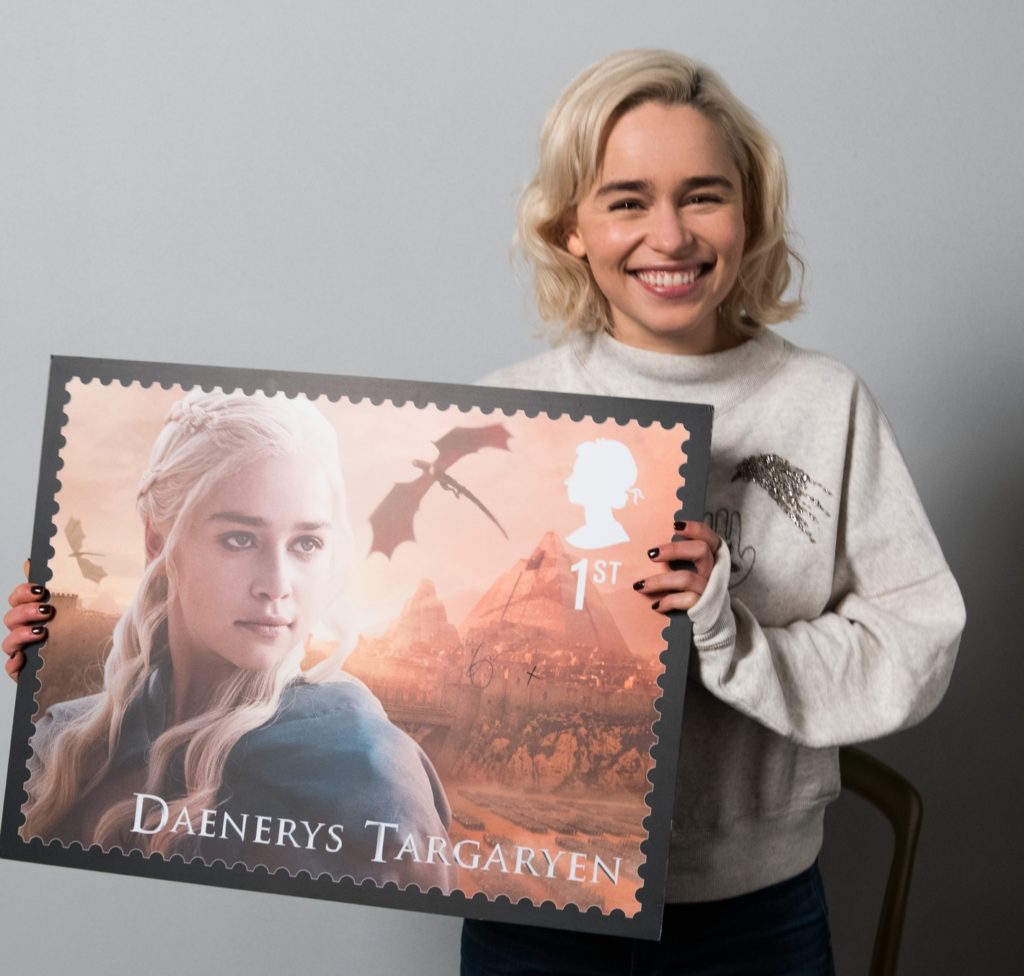 Emilia Clarke holding a print of the UK Mail postage stamp featuring Daenerys Targaryen in 2018.